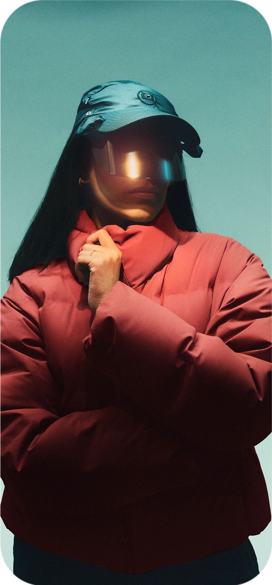 Person wearing a red jacket and the Captured Cap, standing against a muted green background.